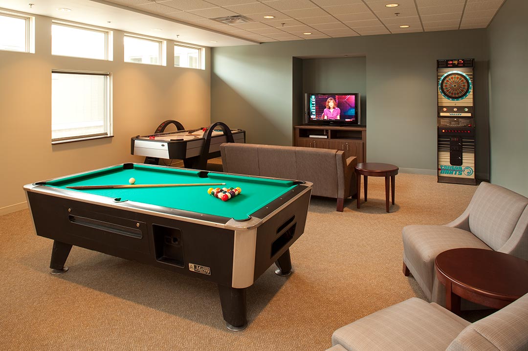 Game room at day service facility featuring pool table, dart board, and air hockey table for recreational activities